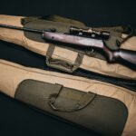 black rifle with scope and brown gig bag