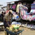 A vender sells pineapples next to a second hand stall at the Gikomba market in Nairobi