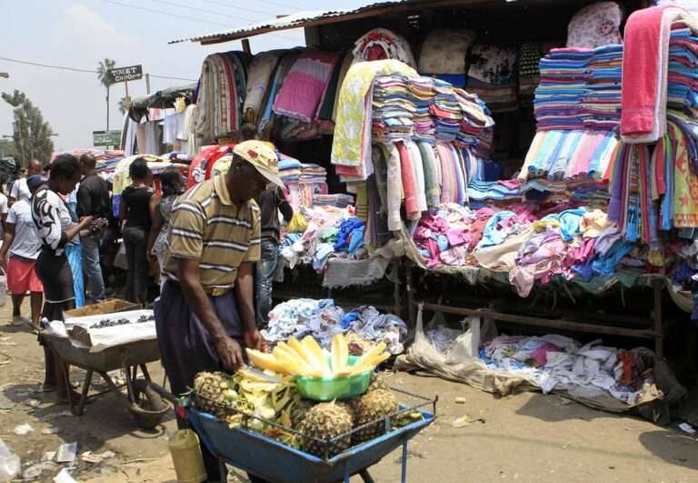 A vender sells pineapples next to a second hand stall at the Gikomba market in Nairobi